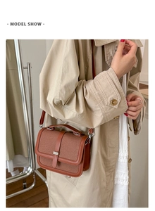 Brown vintage canvas shoulder bag with leather trim worn by a model in a beige coat