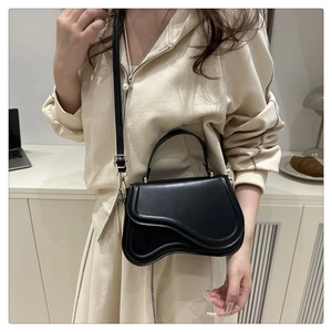 Detail view of a black matte saddle bag with adjustable strap and gold metal hardware