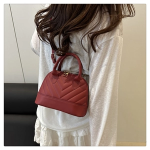 Detailed view of red V-quilted crossbody bag with golden hardware on female model
