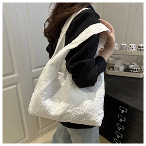 Detail of white floral embroidered canvas tote bag featuring delicate lace textures