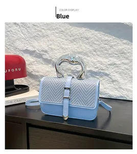 Detail of blue textured handbag with woven flap and unique silver metal handle