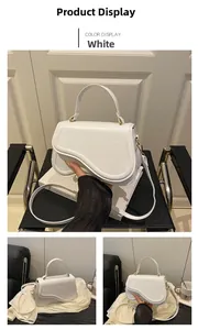 Detail view of white PU leather saddle bag with gold hardware and top handle