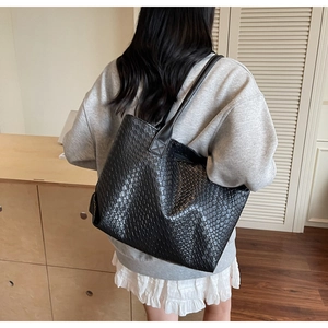 Close-up of black woven texture tote bag worn on shoulder for a minimalist look