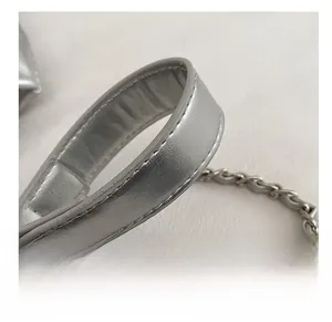 Detail of silver quilted bucket bag featuring a wide strap and metal chain link handle