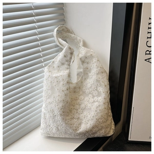 Détail du sac cabas en dentelle blanche avec broderies florales et maille transparente