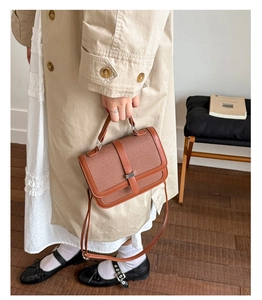 Brown canvas and leather handbag shown from a top-down angle in a cozy home setting