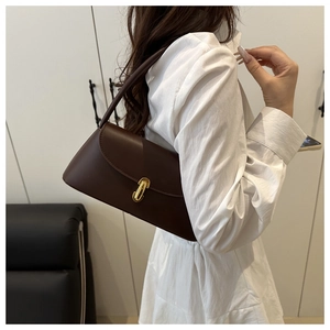 Detail of minimalist dark brown underarm bag with elegant gold oval buckle and matte finish