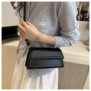 Close-up of classic black leather crossbody bag with double stitching and thin strap