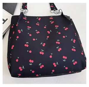Detail of cherry print nylon tote with metal rings and black woven straps