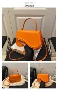 Detail view of orange saddle bag with asymmetrical flap and adjustable shoulder strap