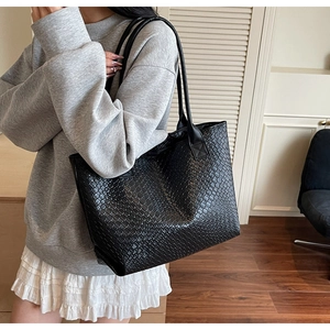 Detailed macro view of black woven texture and high-quality PU leather on a tote bag