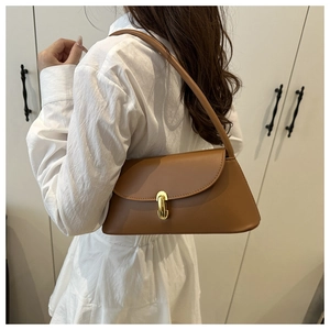 Detail of caramel brown matte leather shoulder bag with gold metal clasp on a model