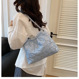 Detail of light blue quilted bucket bag with silver star ornament and chain strap