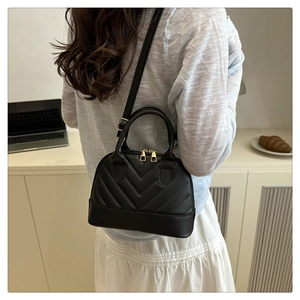 Detail view of the black quilted crossbody bag showing shell silhouette and zip closure