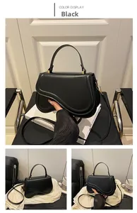 Detail of black curved flap handbag with gold buckle and detachable shoulder strap