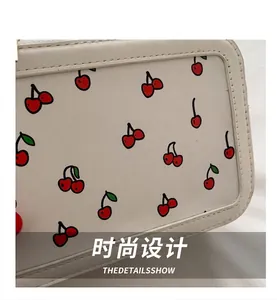 Primer plano del bolso de cuero blanco con motivos de cerezas rojas y costuras finas