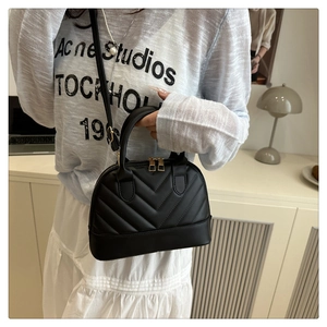 Detail of black chevron shell bag with gold zippers and adjustable shoulder strap