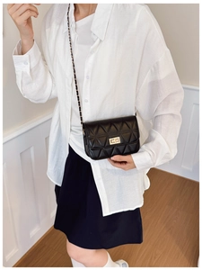 Quilted black crossbody bag featuring a golden twist-lock and metal chain shoulder strap