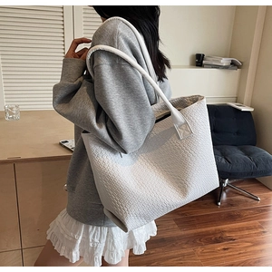 Detailed close-up of the woven texture and reinforced handles on a white tote bag