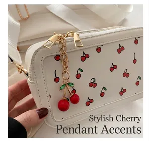Detalle de un pequeño bolso bandolera blanco con estampado de cerezas y colgante 3D