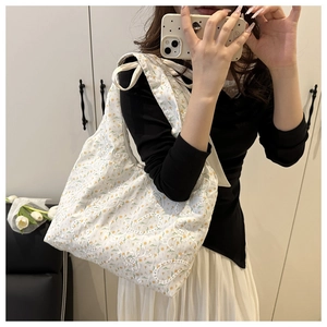 Close-up of floral embroidery and bow tie strap details on a white canvas tote bag