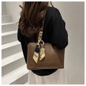 Detail of brown leather tote bag with a decorative chain-pattern silk scarf on handle