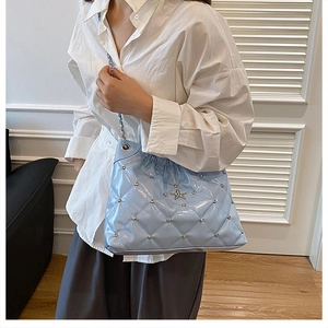 Detail of light blue quilted bucket bag featuring a star buckle and silver chain strap