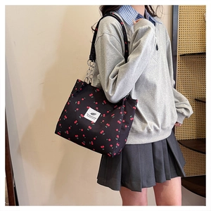 Detailed view of black cherry print tote bag with chain straps on a model in-use