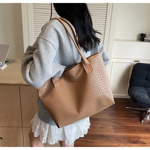 Detail of large brown woven leather tote bag with classic crisscross pattern texture