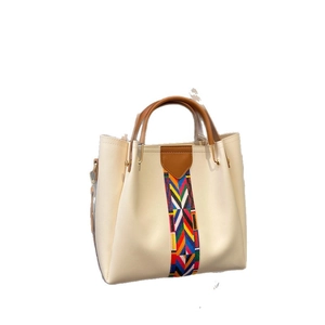 Minimalist beige handbag with brown handle and colorful geometric woven strap detail