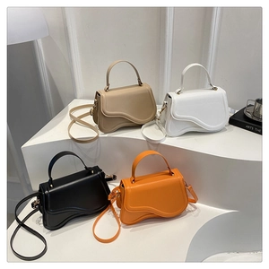 Close-up of minimalist saddle bags in four colors with unique wavy base and top handles