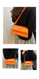 Detail view of vibrant orange crossbody bag featuring premium texture and adjustable strap