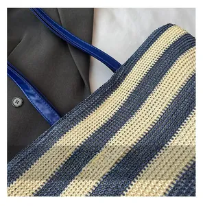 Dettaglio della trama intrecciata a righe blu e bianche con manici in pelle blu