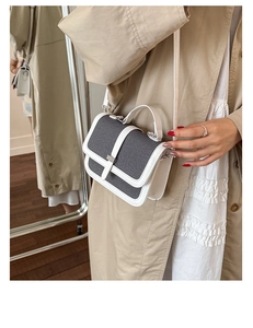 Detail of a textured fabric and white faux leather crossbody bag with gold hardware