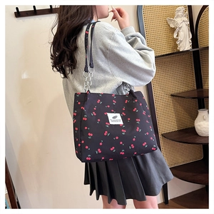 Detail of a black cherry print tote bag featuring metallic chain straps and spacious design