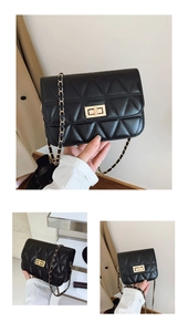 Detail of black quilted crossbody bag featuring golden turn-lock and chain strap