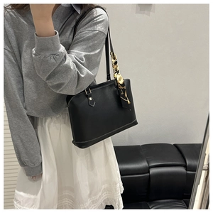 Detail of black leather tote bag featuring elegant patterned scarf handle and sleek texture