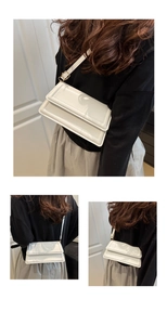 Detail of white glossy leather crossbody bag with double layered flap and gold buckle