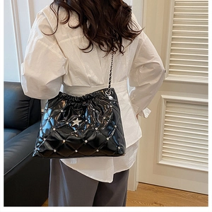 Close-up of black quilted bucket bag with silver metal studs and large star detail