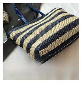 Dettaglio ravvicinato della borsa tote intrecciata a righe blu e beige con manici in pelle