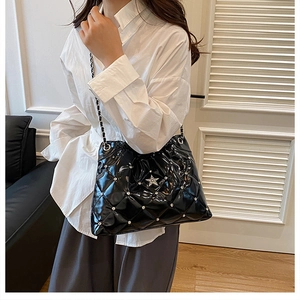 Close-up of black quilted leather bucket bag with silver star studs and chain strap