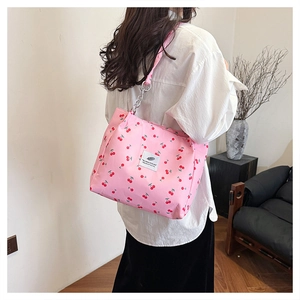 Close-up of pink canvas tote featuring cherry prints and stylish silver metal chain strap