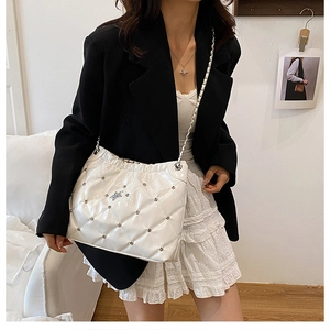 Detail showing white quilted chain bucket bag with silver stars on leather