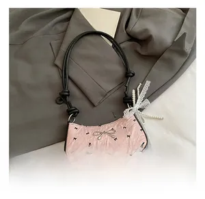 Close-up of pink ruched shoulder bag with bow prints and pearl lace charm detail