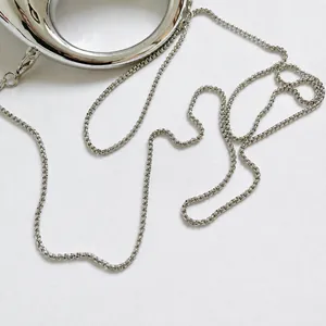 Close-up of polished silver metal circular handle and fine chain strap of the bag