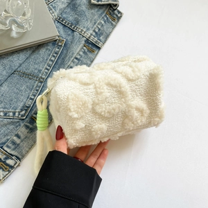 White plush handbag with 3D floral texture and braided strap held in a casual setting