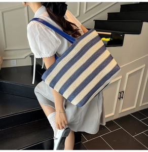 Blue and white striped woven tote bag with dark blue leather straps on a model