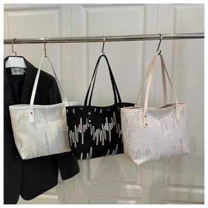Detailed view of large tote bags in white, black, and pink with wave pattern embroidery