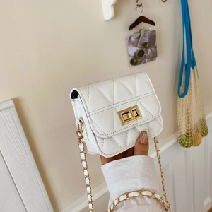 Sac à bandoulière matelassé blanc avec chaîne dorée présenté dans un décor épuré