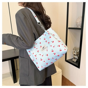Detail of light blue cherry print tote bag with silver chain strap and logo patch